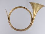 an antique brass french horn on a stand against a white background