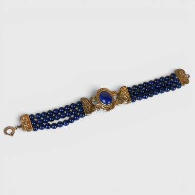 un gros plan sur un bracelet en perles bleues muni d'un fermoir doré