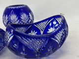 three cobalt blue glass bowls sitting on top of a white surface