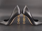 a pair of black high heels with gold chains on the toes