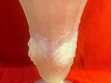 un vase en verre orné d'un visage, posé sur un tissu rouge