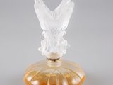 un flacon de parfum en verre orange surmonté d'un papillon