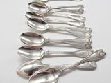 six silver spoons are lined up in a row on a white surface