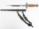 a close up of a knife on a white surface with a chain