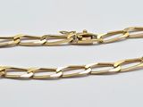gros plan d'un bracelet en chaîne en or sur une surface blanche