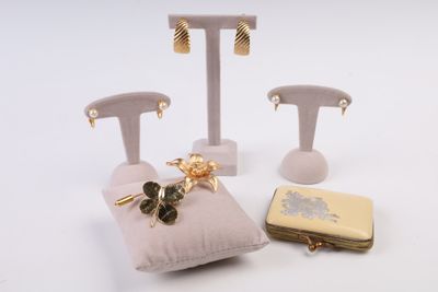 trois paires de boucles d'oreilles et un sac à main posés sur une surface blanche