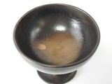 a black bowl with a brown substance in it on a white surface