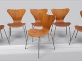 six chaises en bois aux pieds métalliques alignées contre un mur blanc