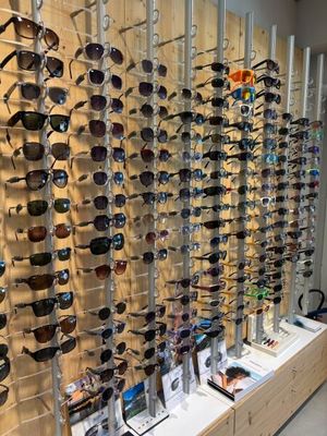 many different shades of sunglasses on display in a store