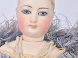 a doll that is wearing a blue dress and a pearl necklace