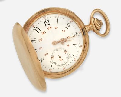 une montre de poche en or posée sur une surface blanche