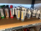 many cans of paint sitting on a shelf in a room