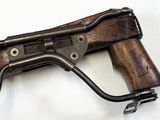 an old machine gun with a wooden handle on a white surface