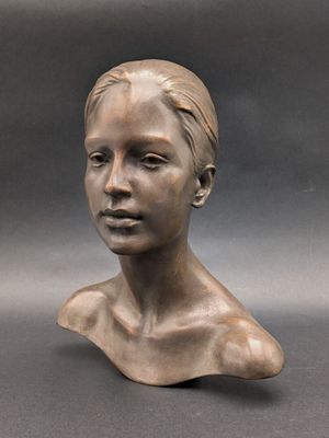 sculpture en bronze représentant la tête d'une femme sur fond gris