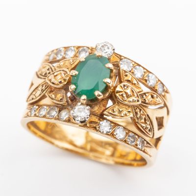 a close up of a gold ring with a green stone surrounded by diamonds