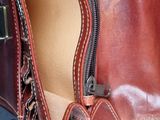 a person holding a brown purse with a zipper