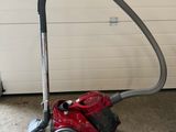 red and black vacuum cleaner on the floor in front of a garage door