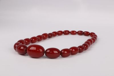 a red beaded necklace with two round beads on a white background