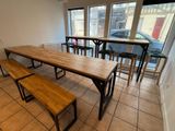 a table and benches in a room with a car in the background
