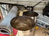 a large metal pot sitting on the floor next to a metal pipe
