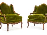 une paire de fauteuils en velours vert avec des pieds en bois sculpté