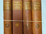 quatre livres sont alignés sur une surface blanche