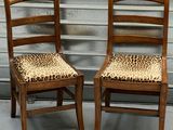 pair of wooden chairs with leopard print seat covers