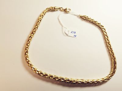 a close up of a gold necklace on a white surface