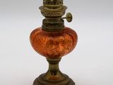 une image représentant une lampe en verre rouge posée sur un pied, sur une surface blanche