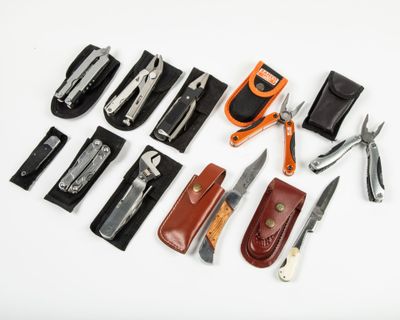 many different types of knives and sheaths laid out on a white surface