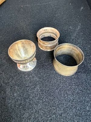 Trois tasses en métal sont posées les unes à côté des autres sur un sol recouvert de moquette.
