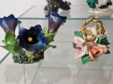 three figurines of flowers on display on a glass table