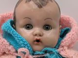 a doll that is wearing a pink and blue jacket