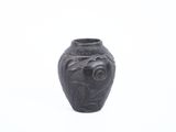 un vase noir orné d'un oiseau sur un fond blanc