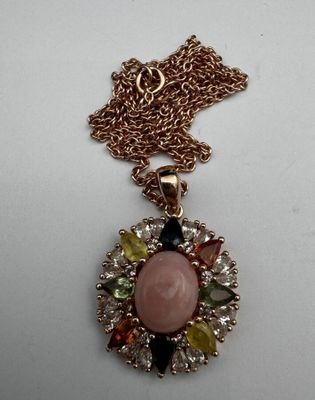 un gros plan d'un collier orné d'une pierre rose entourée de pierres multicolores