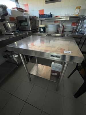 une grande table en acier inoxydable au milieu d'une cuisine