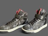 pair of black and red high top sneakers on a grey background