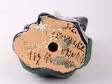 a small blue and green vase with writing on it
