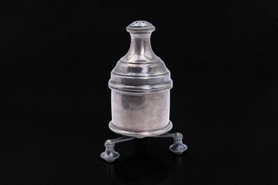 an old silver bottle on a stand against a black background