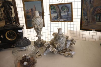 une table avec deux vases, une horloge et des tableaux au mur