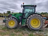 a green tractor that is parked in the dirt