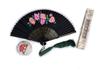 a black fan with pink flowers on it next to a ruler
