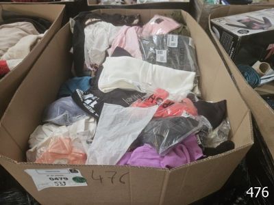 une boîte en carton remplie de vêtements divers, posée par terre