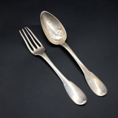 two silver spoons and a fork on a black surface