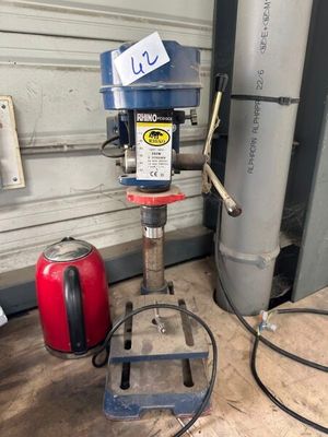 une perceuse posée sur une table dans un garage, avec un tuyau d'arrosage