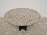 a marble table with a black base on a cement floor