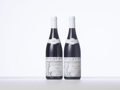 two bottles of red wine sitting on top of a white table