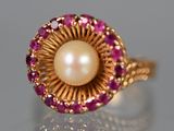 Gros plan sur une bague ornée d'une perle et d'un rubis, posée sur une surface réfléchissante