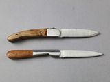 two knifes with wooden handles on a table with a gray surface