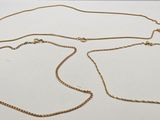 trois colliers en or posés sur une surface blanche, sur fond blanc